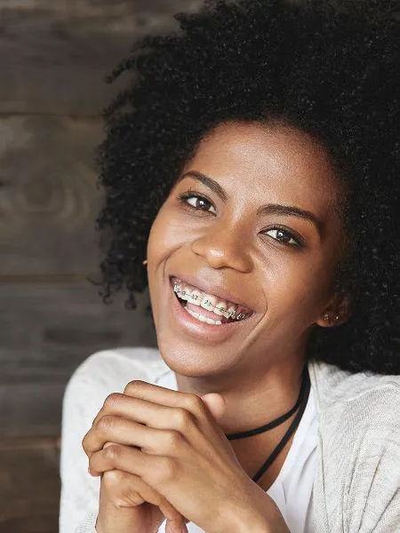 Smiling woman with curly hair in casual white shirt against neutral background, professional headshot style portrait.