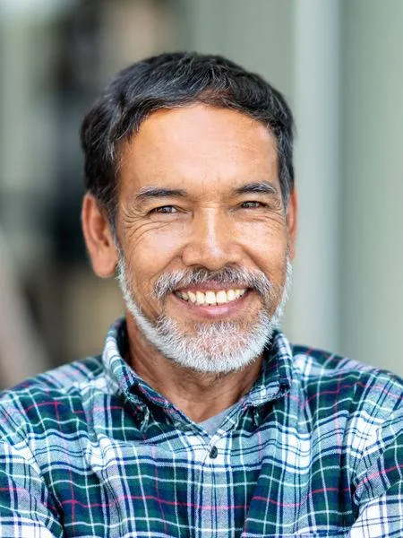 Smiling man in plaid shirt, professional headshot for dental practice website.