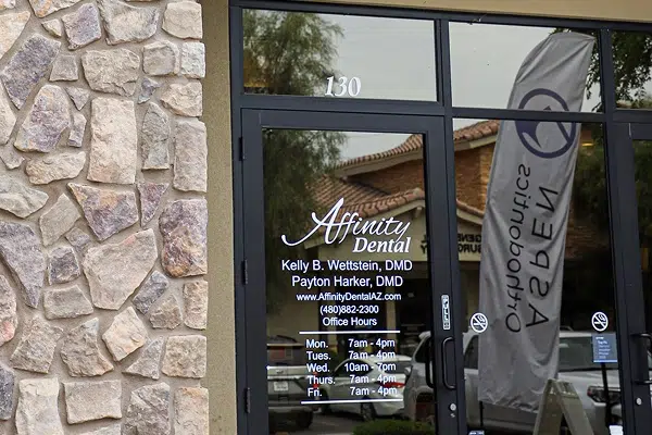 Affinity Dental storefront entrance with glass doors and signage on stone building exterior.